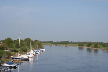 Boote ankern entlang eines grünen Flussufers bei klaren Himmel, perfekt für Wassersportfreunde.