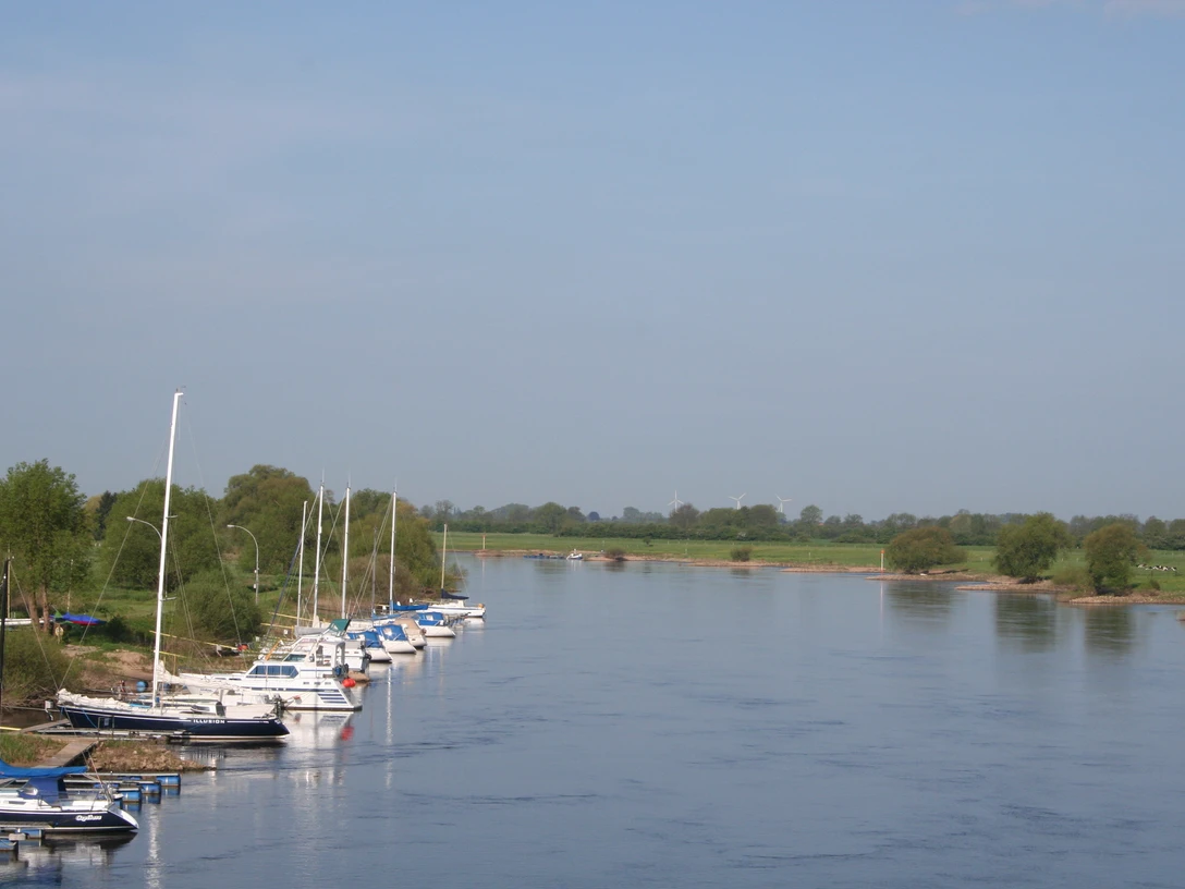 Boote ankern entlang eines grünen Flussufers bei klaren Himmel, perfekt für Wassersportfreunde.