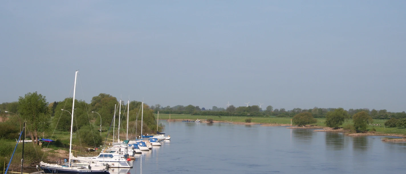 Bootsportverein Achim-Thedinghausen Boote ankern entlang eines grünen Flussufers bei klaren Himmel, perfekt für Wassersportfreunde.