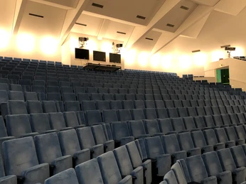 Theatersaal Nienburg Sitzreihen in einem modernen Theatersaal mit blauen Polstern, von einem sanften Licht erhellt.