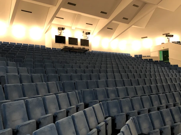 Theatersaal Nienburg Sitzreihen in einem modernen Theatersaal mit blauen Polstern, von einem sanften Licht erhellt.