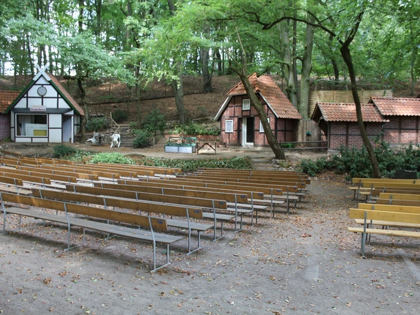 Freilichtbühne Marklohe mit Holzbänken vor rustikalen Bühnenhäusern im Wald, herbstlich umrahmt.
