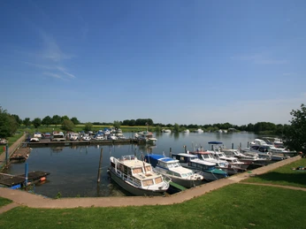 Marina Mehlbergen Eine harmonische Uferlandschaft mit ankernden Freizeitbooten in einem weitläufigen Hafenbecken.