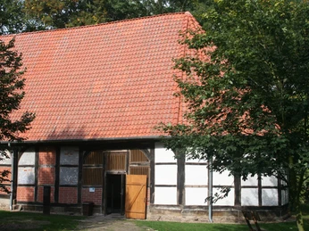 Kloster Schinna Backsteingebäude mit rotem Satteldach und Fachwerk, umgeben von Bäumen und grünem Laub.Brick building with red saddle roof and half-timbering, surrounded by trees and green foliage.Murstensbygning med rødt sadeltag og bindingsværk, omgivet af træer og grønt løv.Bakstenen gebouw met rood zadeldak en vakwerk, omringd door bomen en groen gebladerte.