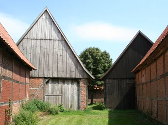 Scheunenviertel Schlüsselburg Drei historische Fachwerkscheunen mit roten Ziegeldächern in einer malerischen ländlichen Umgebung.