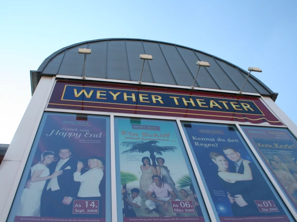 Weyher Theater Eingang des Weyher Theaters mit großen, farbenfrohen Werbepostern der aktuellen Aufführungen.