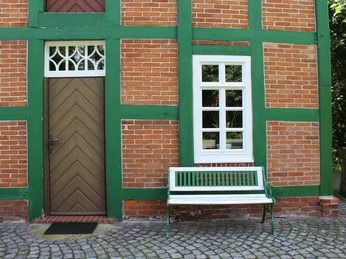Spieker Lahausen Historisches Backsteingebäude mit grünen Holzbalken und Bank daneben, umgeben von Natur.