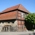 Wassermühle Sudweyhe Fachwerkgebäude der Wassermühle Sudweyhe mit rotem Ziegeldach und grünem Laubbaum.