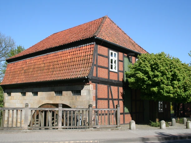 Wassermühle Sudweyhe Fachwerkgebäude der Wassermühle Sudweyhe mit rotem Ziegeldach und grünem Laubbaum.