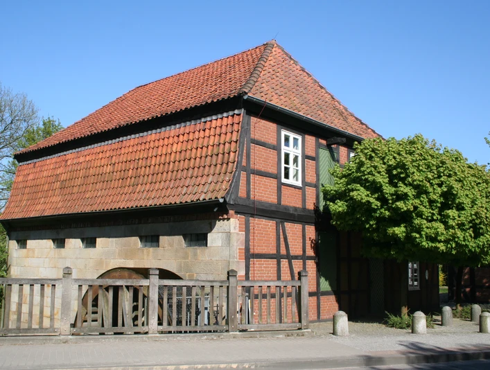 Wassermühle Sudweyhe Fachwerkgebäude der Wassermühle Sudweyhe mit rotem Ziegeldach und grünem Laubbaum.