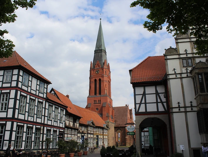 Pfarrkirche St. Martin in Nienburg umgeben von Fachwerkbauten, unter bewölktem Himmel.Parish church of St. Martin in Nienburg surrounded by half-timbered buildings, under a cloudy sky.Martins sognekirke i Nienburg omgivet af bindingsværksbygninger under en overskyet himmel.De parochiekerk St Martin in Nienburg, omringd door vakwerkhuizen, onder een bewolkte hemel.