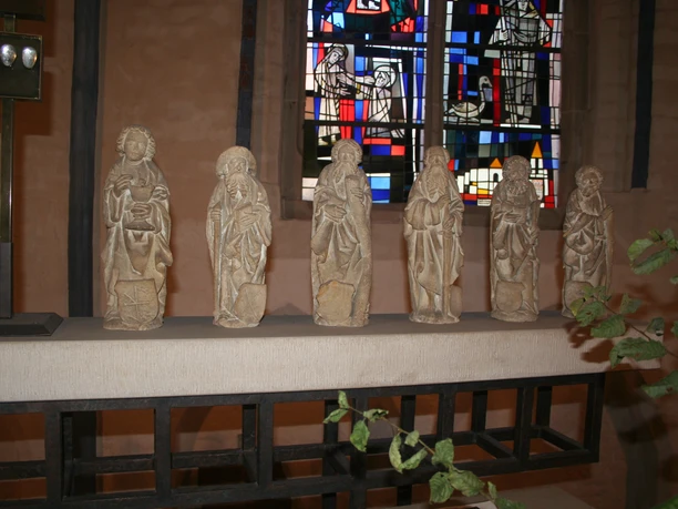 Apostelfiguren in St. Martin Nienburg Sechs steinerne Apostelfiguren stehen in einer Kirchenreihe vor farbigem Glasfenster in Nienburg.