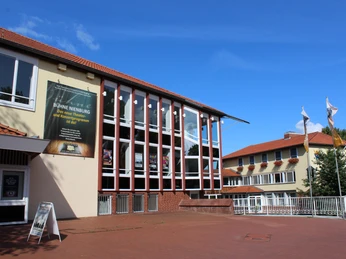 Theater auf dem Hornwerk Theater auf dem Hornwerk in Nienburg, moderner Bau mit großer Glasfront und blauen Himmel im Hintergrund.