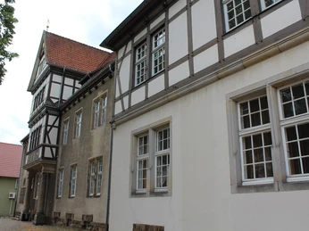 Altes Amtsgericht Petershagen Fachwerkgebäude mit weißen und grauen Wänden sowie roten Dachziegeln und vielen Fenstern in Petershagen.