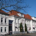 Sparkassengebäude Achim Historisches weißes Gebäude mit rotem Ziegeldach, Sitz der Sparkasse in Achim, Bäume im Vordergrund.