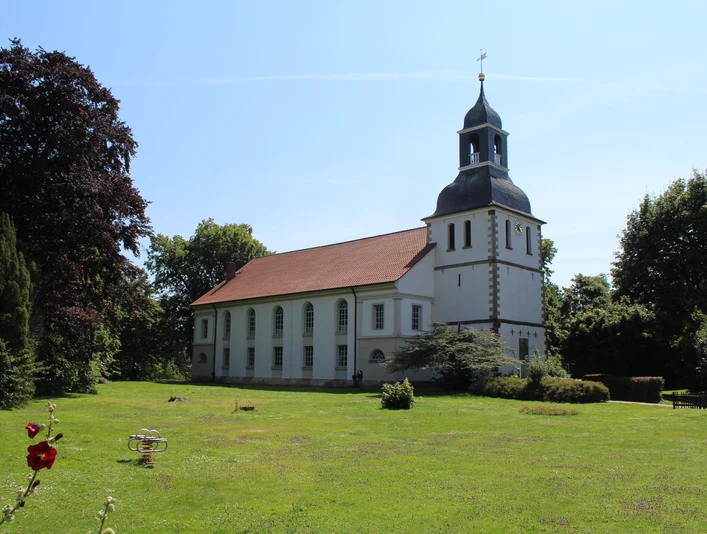 Weiße Kirche mit grauen Schindeln in grüner Parklandschaft unter blauem Himmel in Blender.