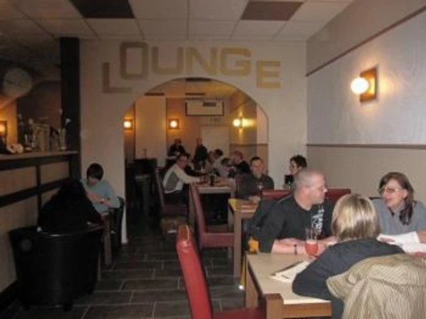 image Gemütliche Lounge mit Gästen, die an Tischen zusammensitzen, in entspannter Atmosphäre.