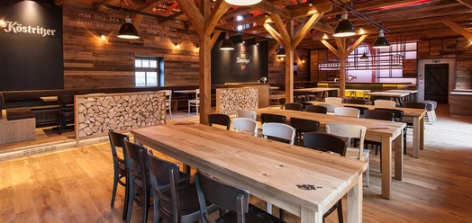 Interior view of a rustic brewery with wooden beams and long wooden tables.