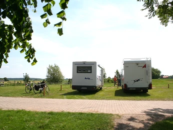 Zwei Wohnmobile stehen auf einer grünen Wiese in Hoya, mit Fahrrädern und weitem Blick auf die Landschaft.