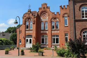 Bauschule Rehburg Backstein-Gebäude der Bauschule Rehburg mit imposanter Fassade und verzierten Fensterbögen bei Sonnenschein.