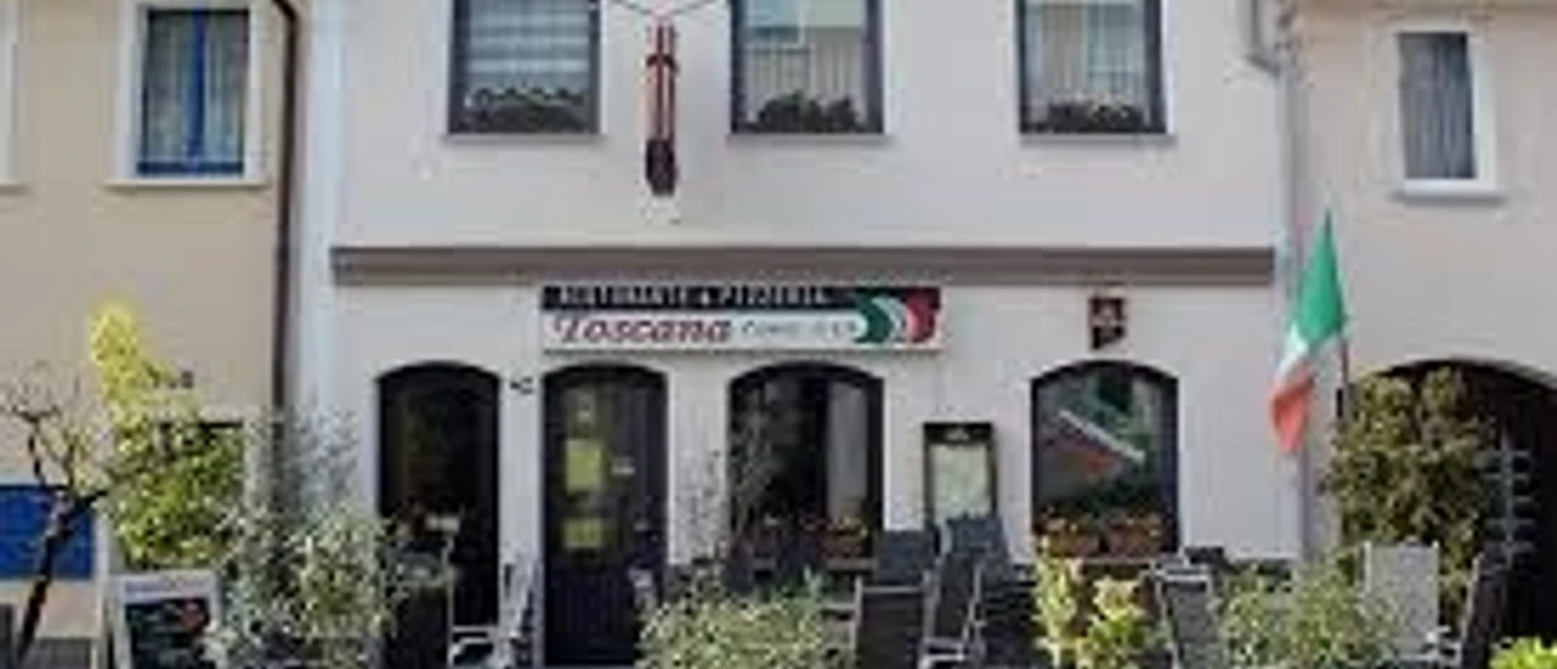 Italian restaurant with outdoor seating area, colorful signs and terracotta pots.