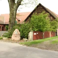 Unser kleiner Hof Wietzen Ein alter Bauernhof mit Backsteingebäuden, umgeben von grünen Bäumen und einem Weg aus Asphalt.