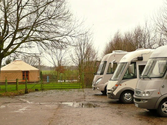 Unser kleiner Hof Wohnmobilstellplätze Wohnmobile stehen nebeneinander auf einem befestigten Stellplatz am Rand eines grünen Feldes.