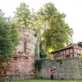 1Diekturm Außenansicht Zwei Personen stehen vor dem Diekturm und schauen sich ein Hinweisschild an der danebenstehenden Mauer an.Two people are standing in front of the tower and looking at a sign on the wall next to it.To personer står foran tårnet og kigger på et skilt på væggen ved siden af.Twee mensen staan voor de toren en kijken naar een bord op de muur ernaast.