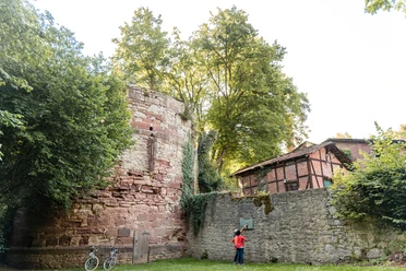 Diekturm Wallanlagen Zwei Personen stehen vor dem Diekturm und schauen sich ein Hinweisschild an der danebenstehenden Mauer an.
