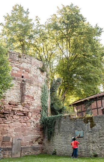 Diekturm Wallanlagen Zwei Personen stehen vor dem Diekturm und schauen sich ein Hinweisschild an der danebenstehenden Mauer an.Two people are standing in front of the tower and looking at a sign on the wall next to it.To personer står foran tårnet og kigger på et skilt på væggen ved siden af.Twee mensen staan voor de toren en kijken naar een bord op de muur ernaast.