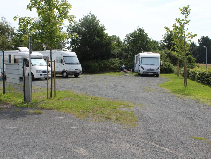 Ein gepflegter Stellplatz für Reisemobile umgeben von Grünflächen und vereinzelt parkenden Wohnmobilen.