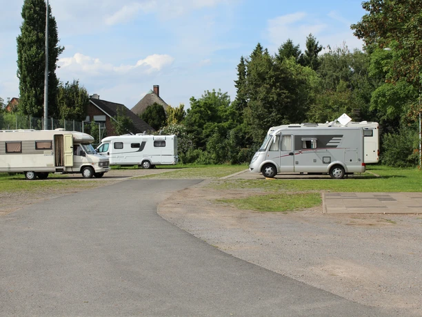 Wohnmobilstellplatz Petershagen Wohnmobilstellplatz in Petershagen mit mehreren geparkten Wohnmobilen, umgeben von Bäumen und Grünflächen.