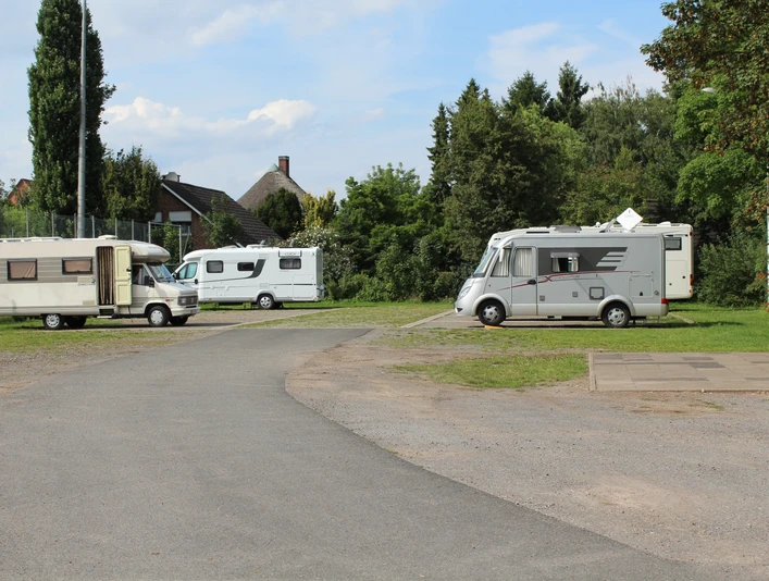 Wohnmobilstellplatz Petershagen Wohnmobilstellplatz in Petershagen mit mehreren geparkten Wohnmobilen, umgeben von Bäumen und Grünflächen.