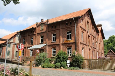 Meyersicksche Mühle Steyerberg Historische Backsteinmühle in Steyerberg umgeben von Natur, mit leicht bewölktem Himmel im Hintergrund.