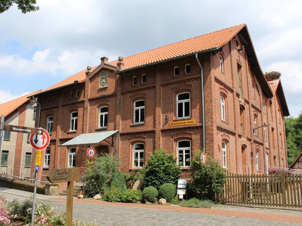 Meyersicksche Mühle Steyerberg Historische Backsteinmühle in Steyerberg umgeben von Natur, mit leicht bewölktem Himmel im Hintergrund.