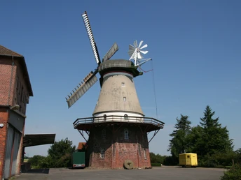 Historische Windmühle in Dörverden, Backsteinbau, blauem Himmel und umliegenden Gebäuden.