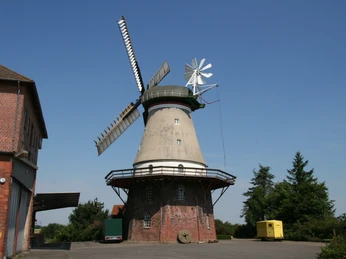 Windmühle Dörverden Historische Windmühle in Dörverden, Backsteinbau, blauem Himmel und umliegenden Gebäuden.