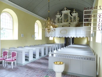 Kirche Woquard Innenraum zu sehen ist die Kirche Woquard von innen, Blick auf die Orgelempore und die hellen Sitzreihen.