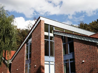 Museen an der Koppelschleuse: Stadtmuseum Meppen Backsteingebäude mit großen Glasfronten und schrägem Dach vor blauem Himmel mit weißen Wolken