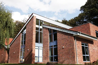 Museen an der Koppelschleuse: Stadtmuseum Meppen Backsteinbau mit großen Glasfronten und moderner Dachform vor grünem Baumbestand bei Sonnenschein