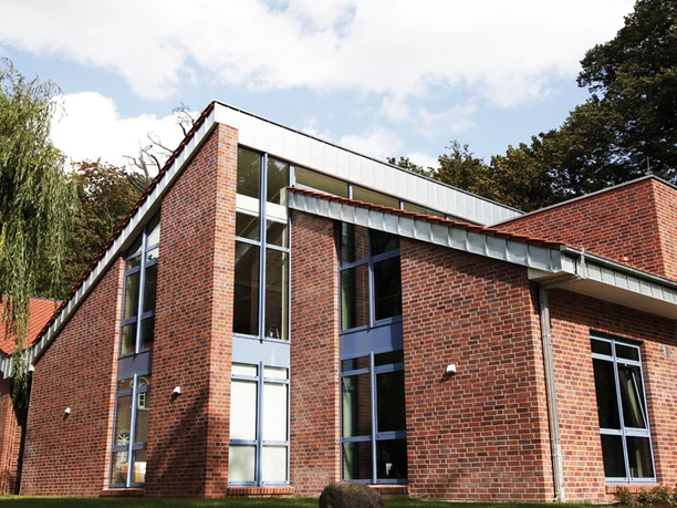 Museen an der Koppelschleuse: Stadtmuseum Meppen Backsteinbau mit großen Glasfronten und moderner Dachform vor grünem Baumbestand bei Sonnenschein