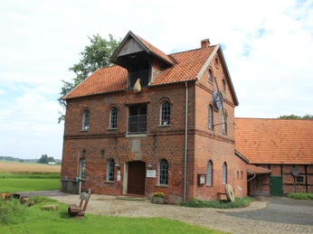 Wassermühle Süstedt Rote Backstein-Wassermühle mit Satteldach, umgeben von Grünflächen und einem gepflasterten Weg.Red brick water mill with gabled roof, surrounded by green areas and a paved path.Vandmølle i røde mursten med sadeltag, omgivet af grønne områder og en asfalteret sti.Rode bakstenen watermolen met zadeldak, omgeven door groene zones en een geplaveid pad.