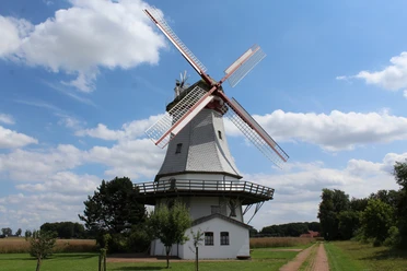 The Behlmer Hochzeitsmühle stands in a green, rural landscape under a clear blue sky.