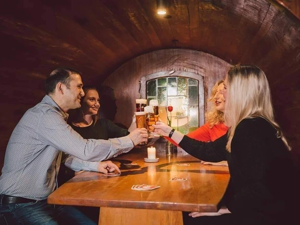Friends sit in an old and huge beer barrel. They are drinking Einbecker beer and enjoying themselves.