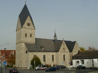 Pfarrkirche St. Johannes Baptist Historische Kirche mit hohem Turm, grauem Steinmauerwerk und einem Uhrziffernblatt über der Kreuzung.