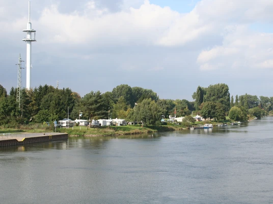 Am Flussufer des Weserflusses gelegener Campingplatz, umgeben von grüner Natur und Bäumen.