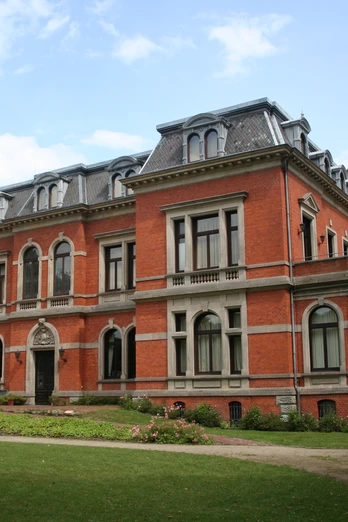 Backsteinfassade des Schloss Etelsen mit grauen Akzenten, umgeben von gepflegten Grünanlagen.