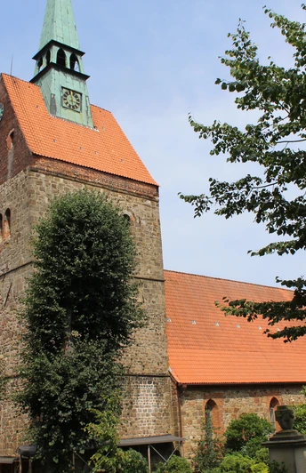 St. Cyriakuskirche Bruchhausen Backstein-Kirche mit grünem Turm, eingebettet in üppiges Grün; architektonisches Erbe.