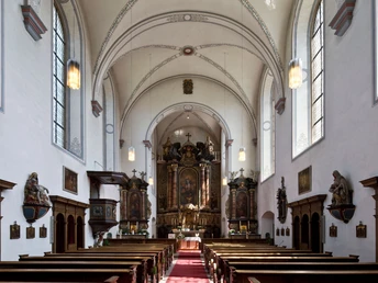 Kapuzinerkirche - Innenansicht Helle Innenansicht der Kapuzinerkirche mit einem reich verzierten Altar und knienden Holzbänken.