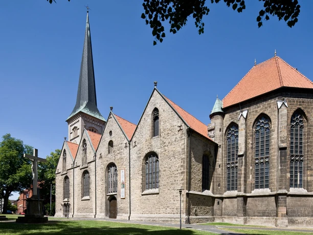 Die Pfarrkirche St. Michael, ein gotisches Bauwerk, steht unter blauem Himmel mit umliegenden Bäumen.